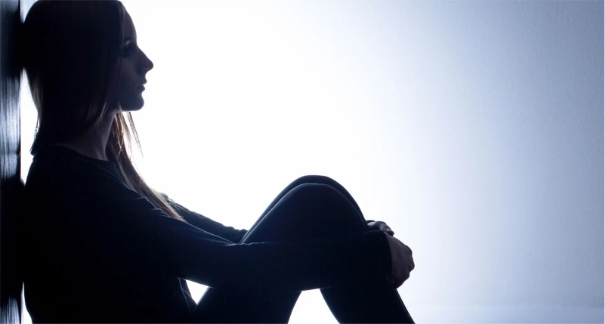 Frau, welche sich mit den Armen um die Beine fässt.