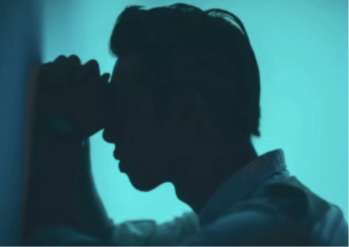 Ein Mann, der mit den Händen und mit dem Kopf an der Wand ist