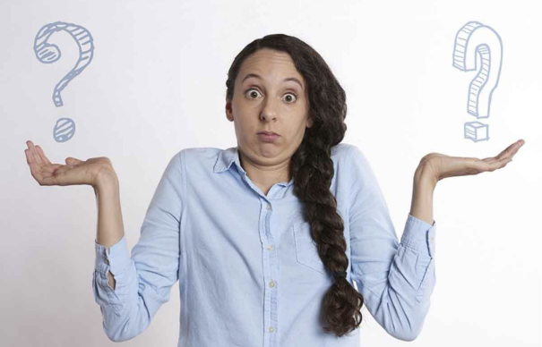 Eine Frau mit Fragezeichen auf den bzw. in den Händen